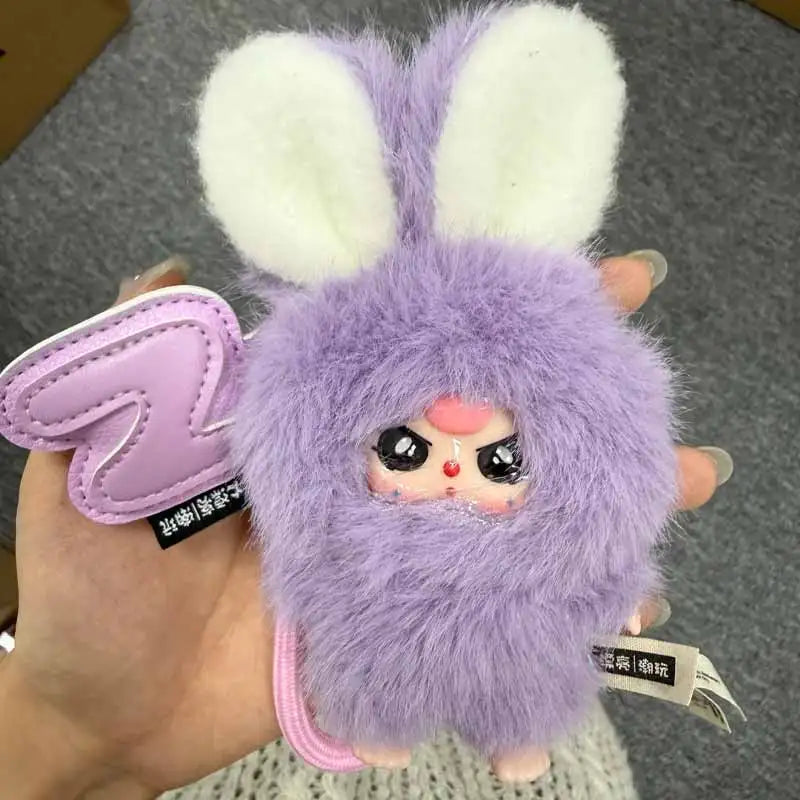 A fluffy purple bunny collectible with white ears and pink accents, held in a hand.