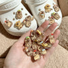 A hand holds several glow-in-the-dark capybara shoe charms next to a white shoe mold.