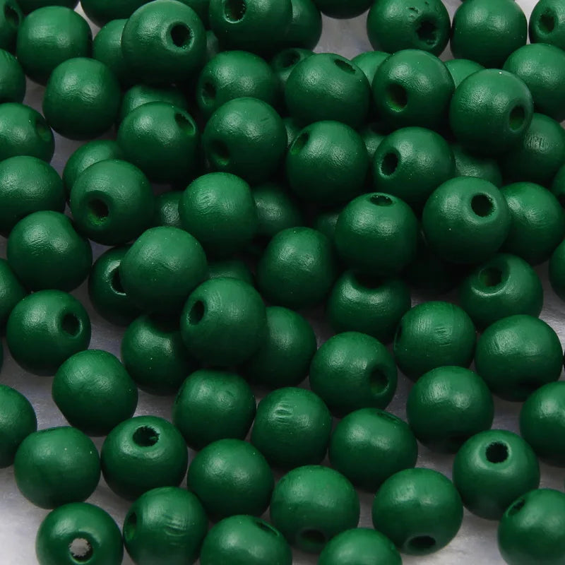 A pile of natural wooden beads in various shades of green for jewelry making and DIY crafts.
