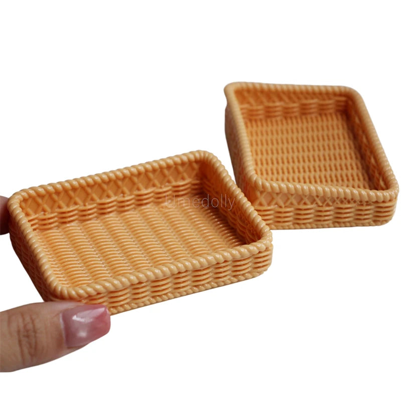 A small, square, woven basket made of light orange wicker or rattan for a miniature dollhouse.