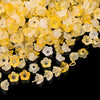 A pile of gradient yellow and white bellflower acrylic beads for jewelry making