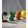 A collection of four wind-up bouncing chick toys in black, green, brown, and yellow sitting on a light surface.