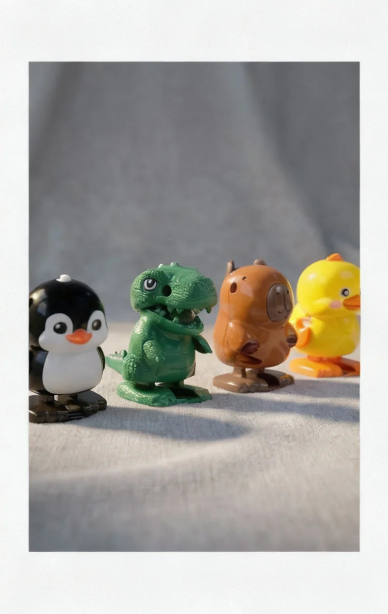 A collection of four wind-up bouncing chick toys in black, green, brown, and yellow sitting on a light surface.