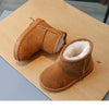 A pair of tan suede winter boots with white faux fur lining resting on brown kraft paper.