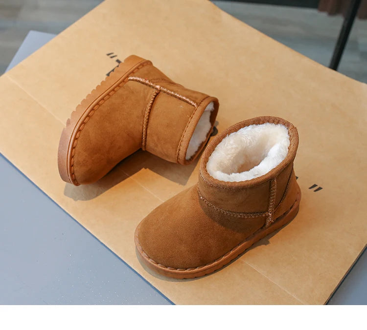 A pair of tan suede winter boots with white faux fur lining resting on brown kraft paper.