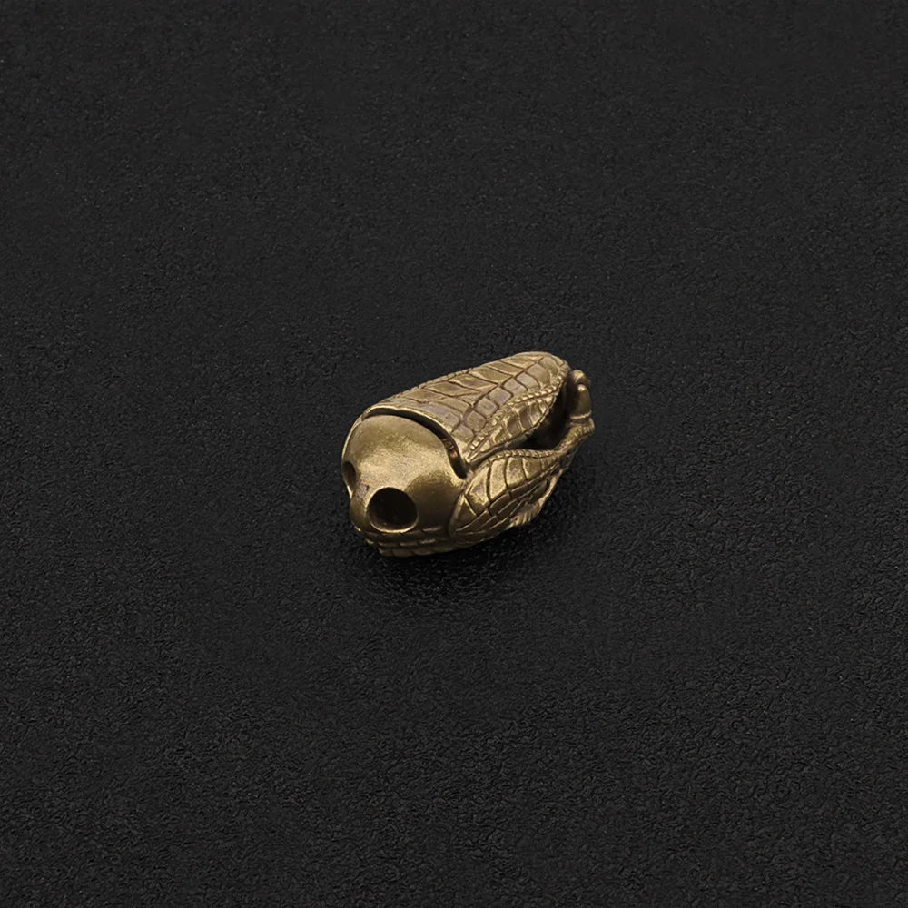 A brass snake head bead used as a paracord lanyard.