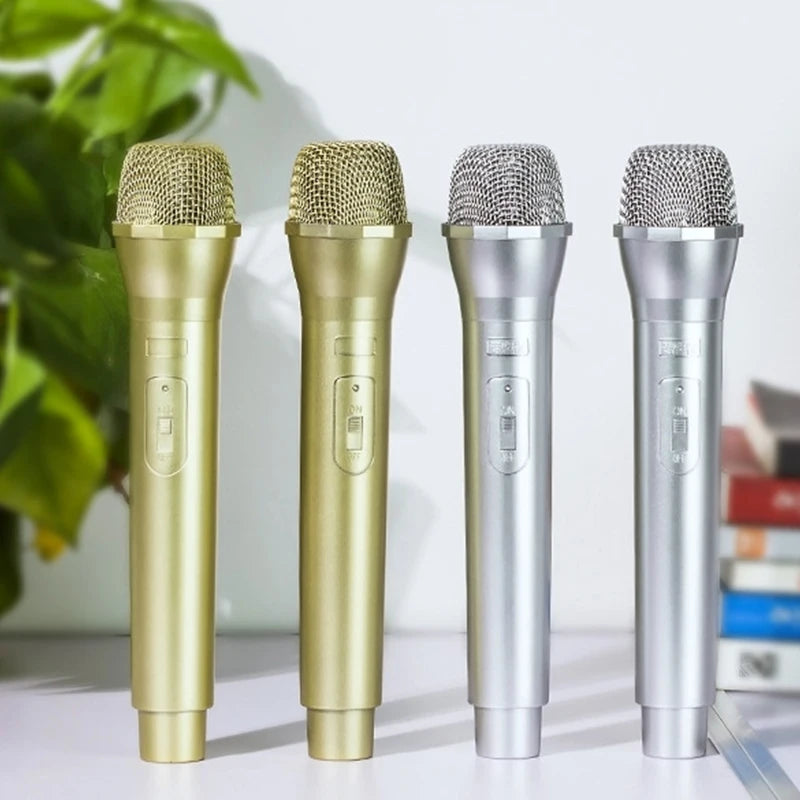 Four realistic toy microphones in gold and silver finishes standing upright on a white surface.