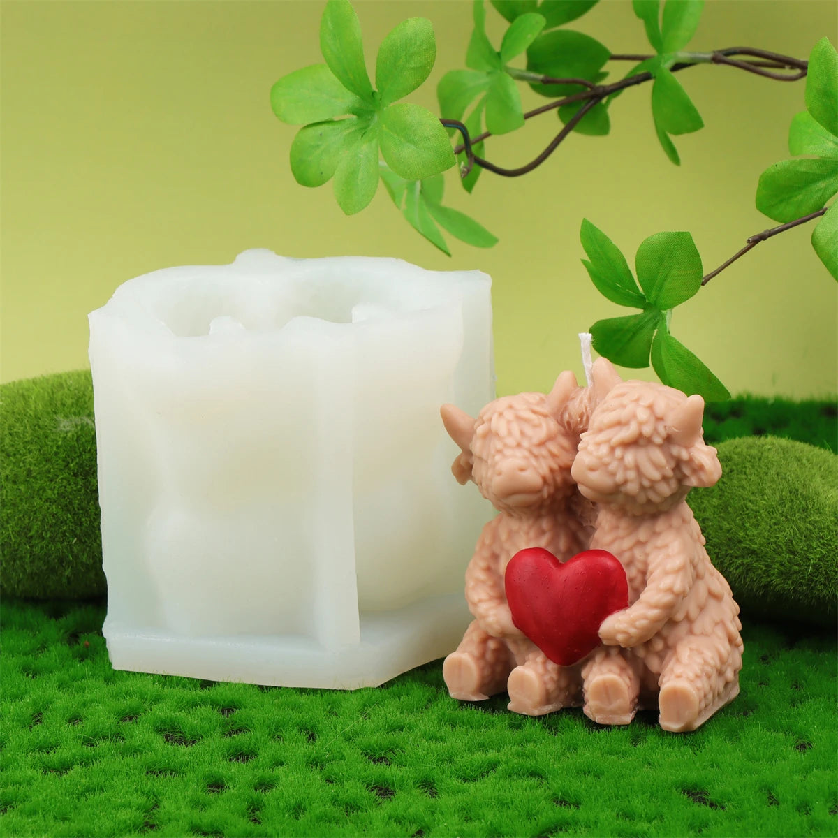 A set of four silicone candle molds shaped like Highland cows resting on green moss.