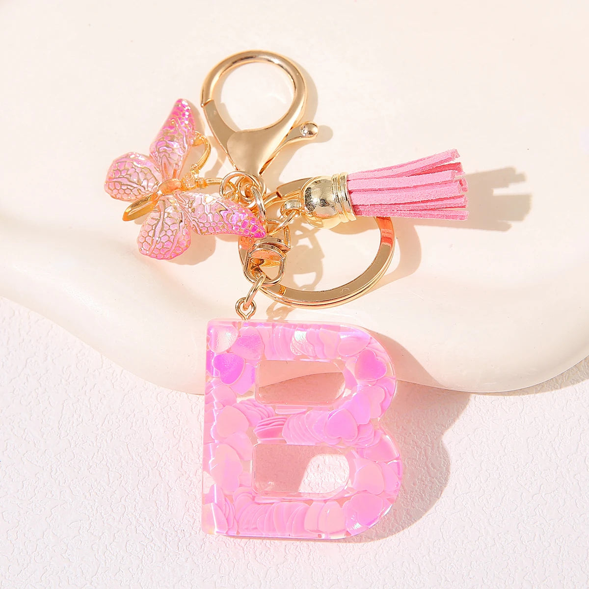 A gold initial heart keychain featuring a pink butterfly charm and a pink acrylic letter B.