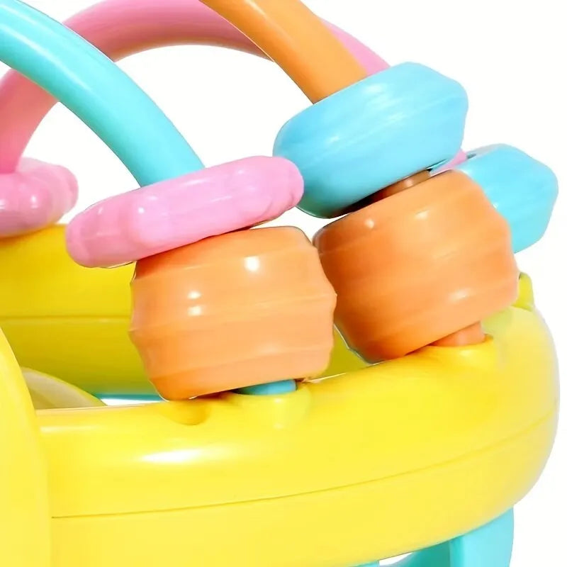 A close-up of a colorful sensory catch ball rattle toy with various colored plastic rings and a yellow base.