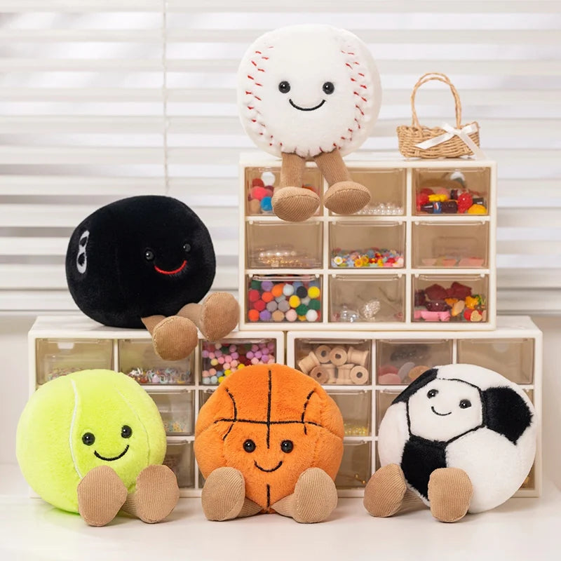 A collection of adorable plush sports balls in various colors and textures with attached feet displayed on a white shelf.