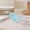 A small, translucent blue squishy toy shaped like a dachshund, resting on a white surface.