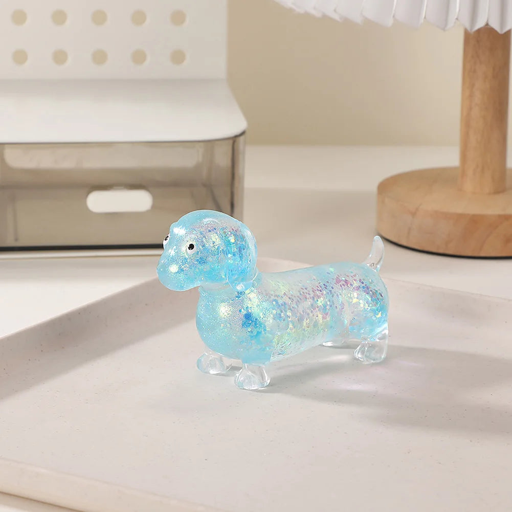 A small, translucent blue squishy toy shaped like a dachshund, resting on a white surface.