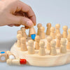 A hand places a wooden memory match stick chess game piece onto a light wood board with other pieces.