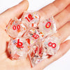 A hand holds a set of pink and clear resin polyhedral dice with numbers on them.