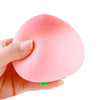 A hand is squeezing a pink, peach-shaped stress relief toy.