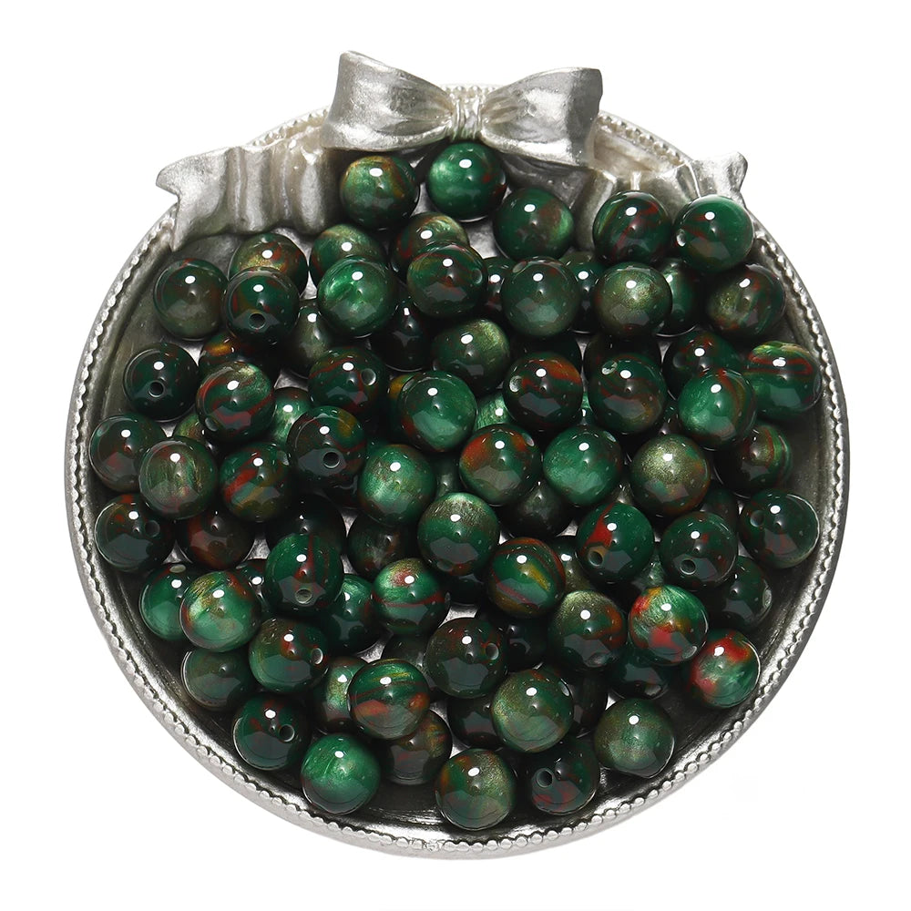 A silver dish filled with round, dark green and reddish-brown glitter resin beads for jewelry making.