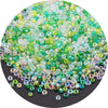 A pile of multi-colored glass rice beads in shades of green, yellow, and purple for crafting.