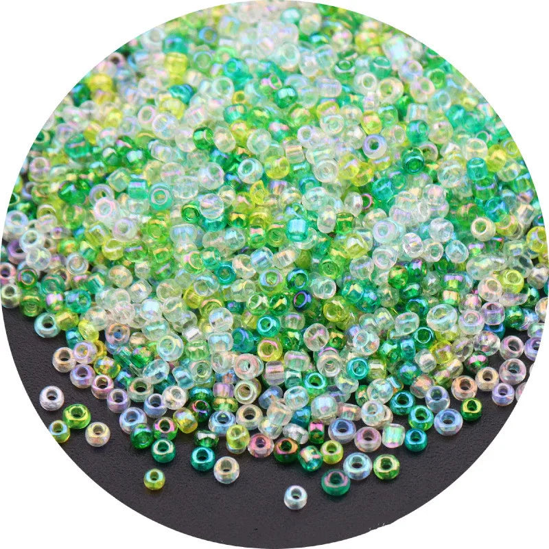 A pile of multi-colored glass rice beads in shades of green, yellow, and purple for crafting.