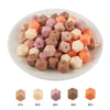A collection of 15 hexagonal silicone beads in various pastel and earthy tones arranged on a white plate.