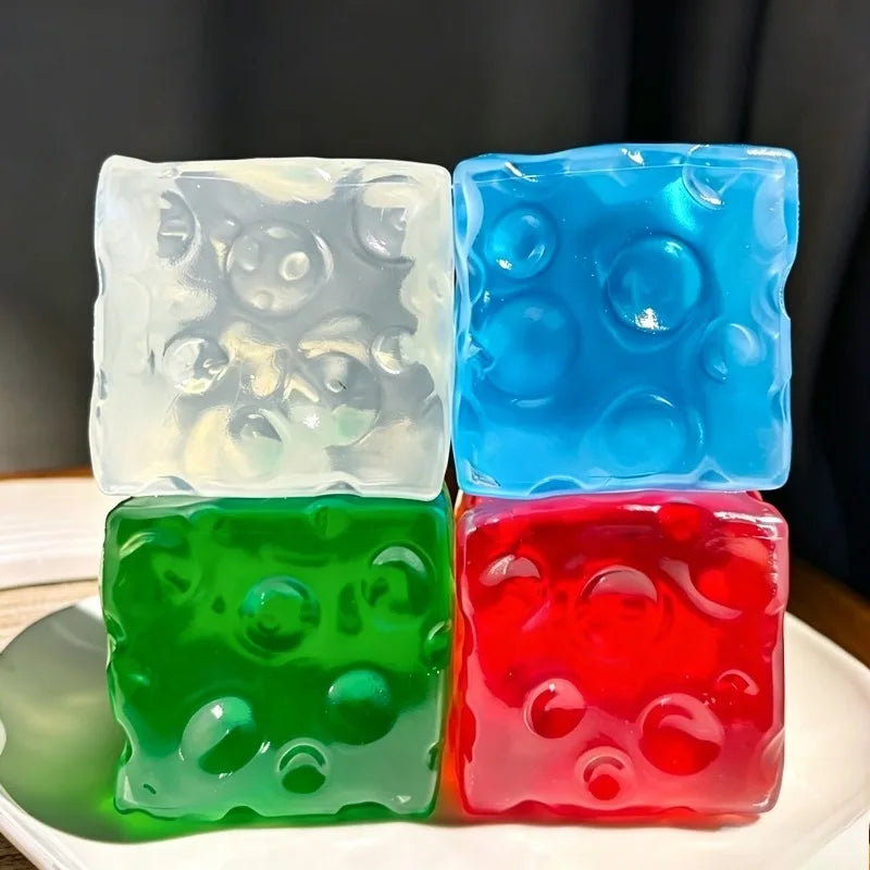Three translucent squishy stress balls in white, blue, green, and red colors