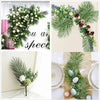 A floral arrangement featuring artificial tropical palm and monstera leaves with roses and greenery for party decor.