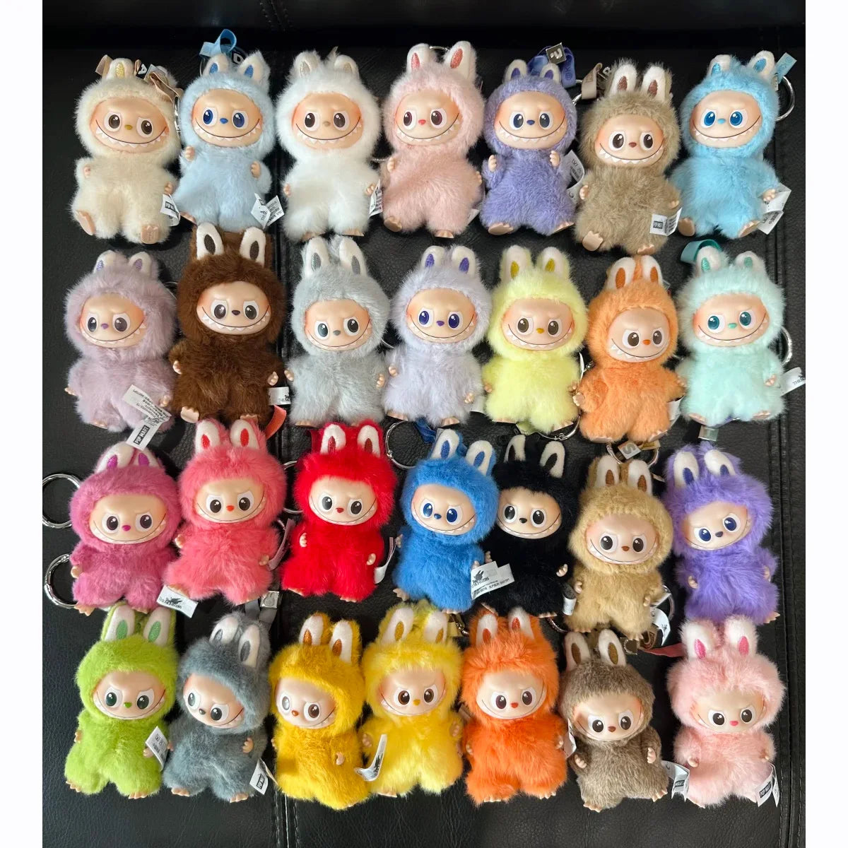 A collection of Labubu V4 pin keychain plush dolls in various pastel colors and textures.