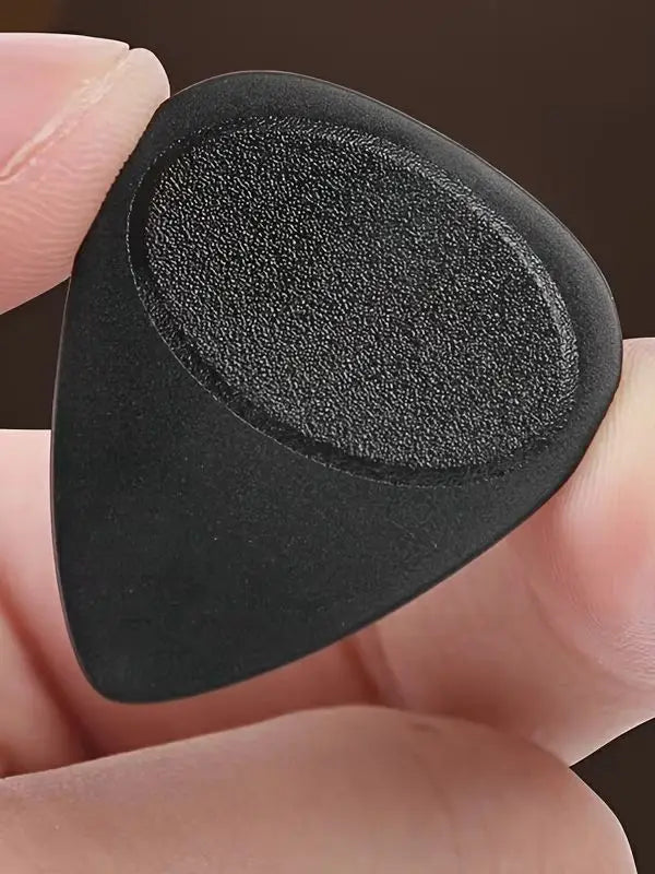 A hand holds a black guitar pick with an anti-slip grip texture.