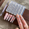 A hand holds silicone nail molds featuring various bowknot designs and a carving pen on a wooden board.