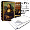 A box of a 1000-piece Mona Lisa jigsaw puzzle with adhesive paper sheets and stacked puzzle pieces.