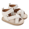A pair of beige and white breathable baby first walker sandals with soft anti-slip soles.