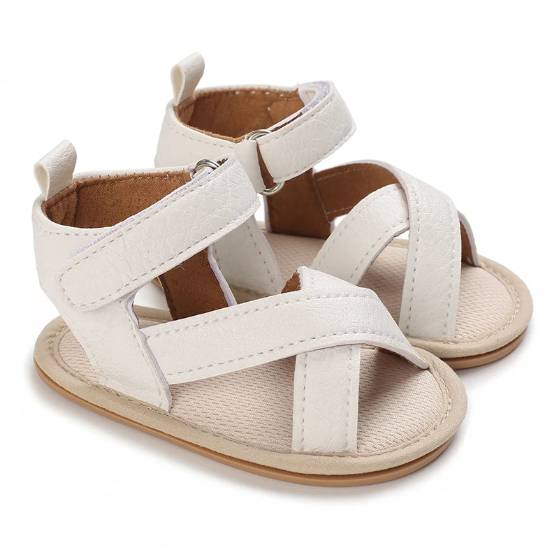 A pair of beige and white breathable baby first walker sandals with soft anti-slip soles.