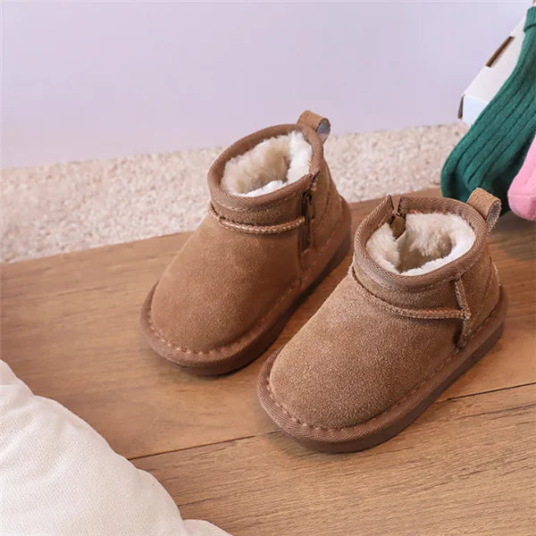 A pair of brown suede winter snow boots with faux fur lining resting on a wooden surface.