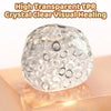 A clear, spherical TPR crystal healing ball resting on a wooden surface.