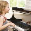 A young girl is playing a piano keyboard with note stickers on the keys.