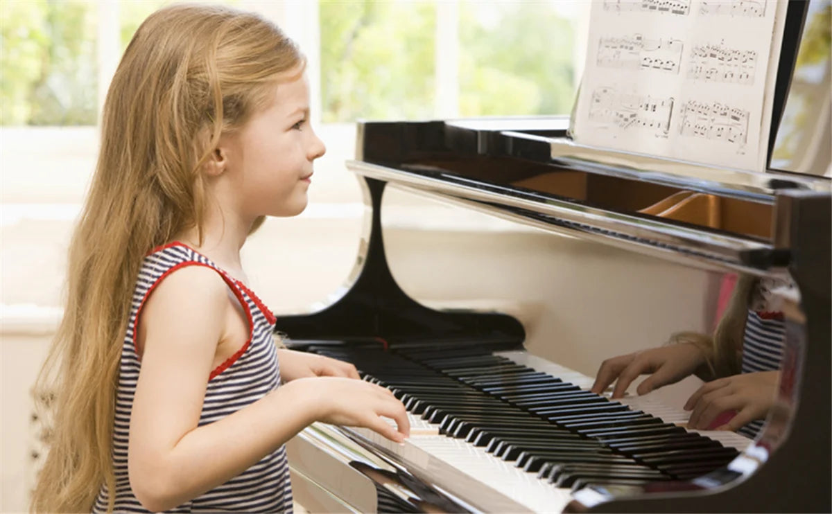 A young girl is playing a piano keyboard with note stickers on the keys.