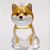 A clear, dog-shaped pet hair keepsake keychain with orange and white markings.