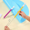 A hand holds a yellow slide whistle toy with a white mouthpiece and a purple slide whistle toy on a light surface.