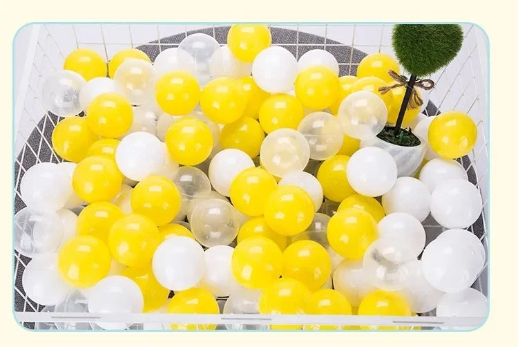 A collection of yellow and white plastic play balls are displayed in a black basket.