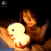 A hand holds a glowing white unicorn LED night light in a dark, intimate setting.