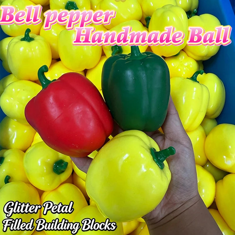 A hand holds a variety of handmade bell peppers in yellow, red, and green colors for building blocks.