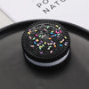 A black squishy stress relief toy with colorful sprinkles resting on a dark plate.