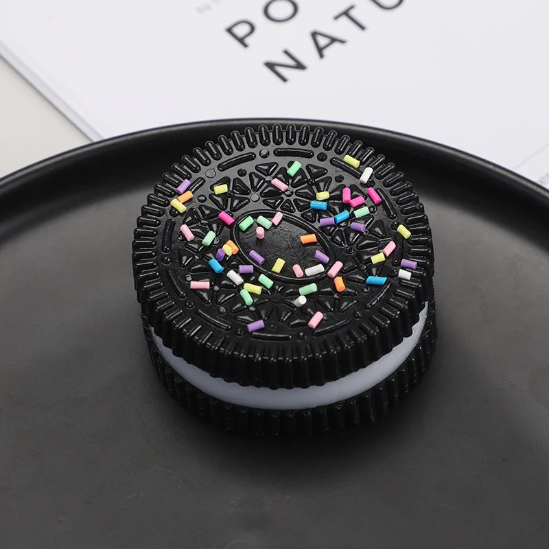 A black squishy stress relief toy with colorful sprinkles resting on a dark plate.