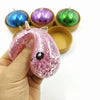 A hand holds a pink glitter unicorn dumpling squishy with a small steamer box, surrounded by other colorful squishies.