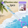 A purple and blue pull-back water gun is shown on a sandy beach with ocean waves in the background.