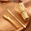 A set of traditional bamboo matcha whisks resting on a wooden plate.