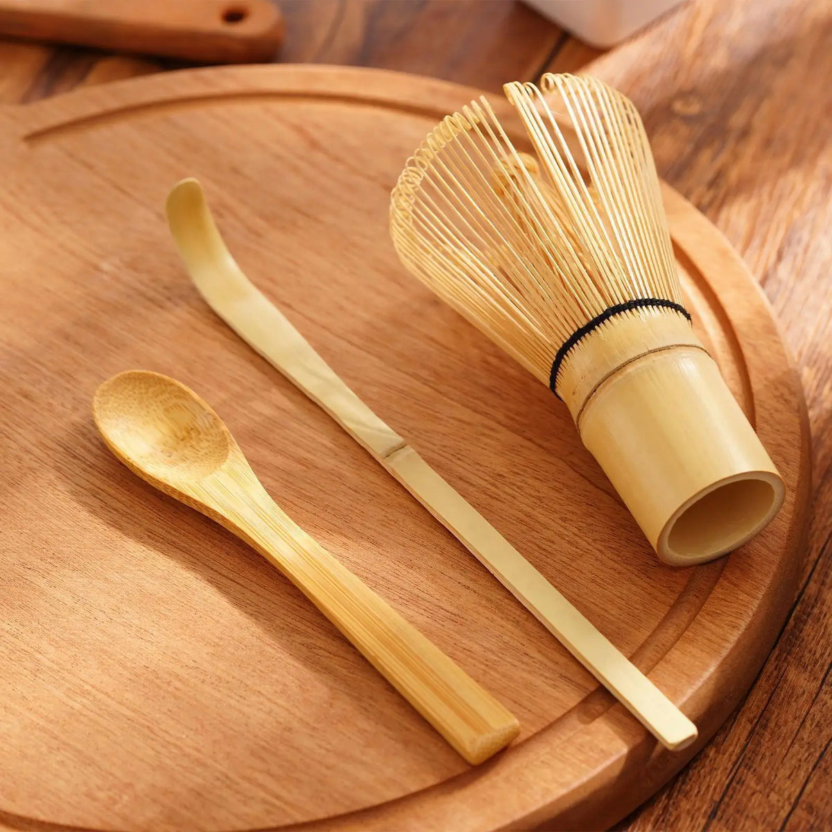 A set of traditional bamboo matcha whisks resting on a wooden plate.