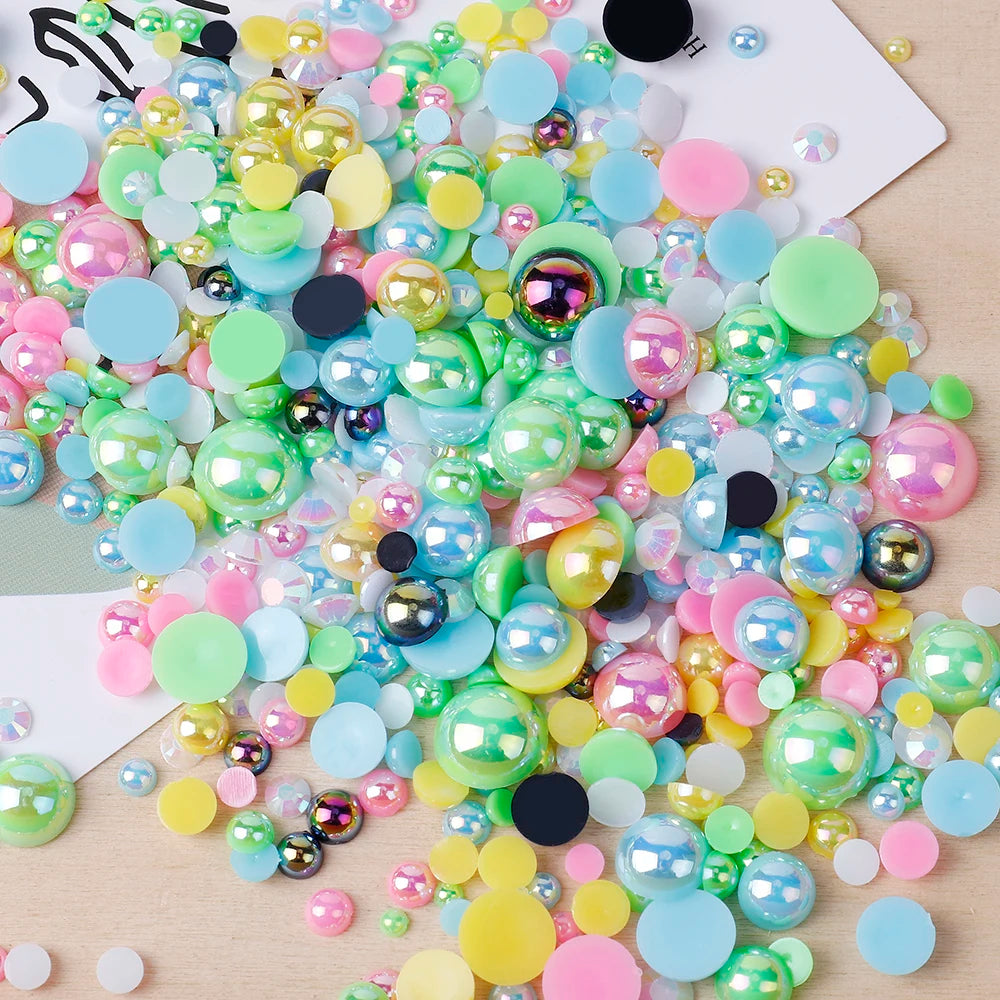 A colorful mix of iridescent resin and rhinestone pearls in various shades of pink, green, yellow, and blue scattered on a li