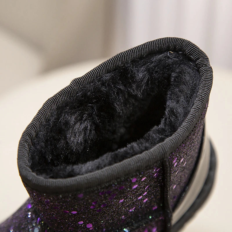 Close-up of a purple sparkly winter snow boot with a black faux fur lining.