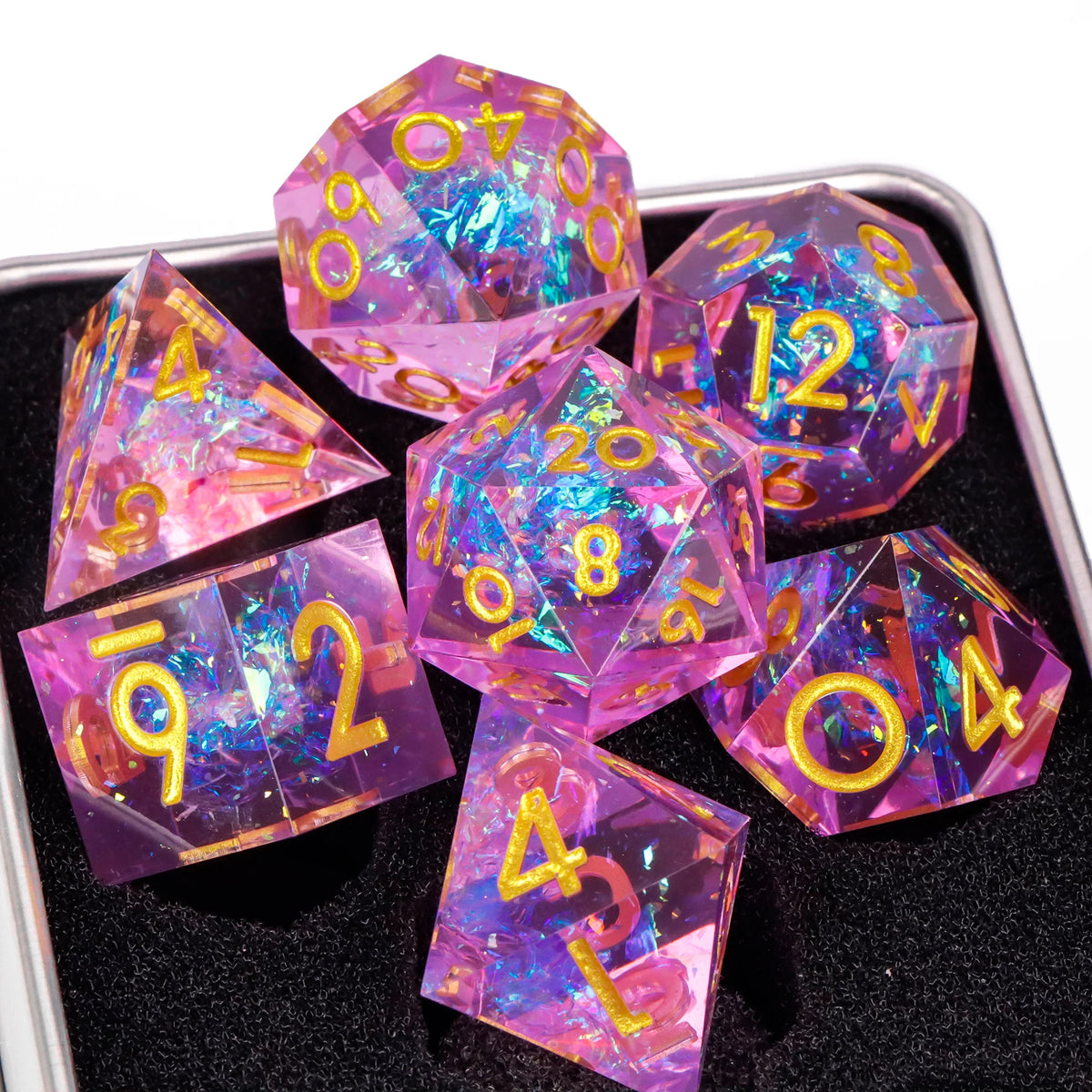 A set of handmade resin sharp edge dice in various colors and shapes resting on a black surface.